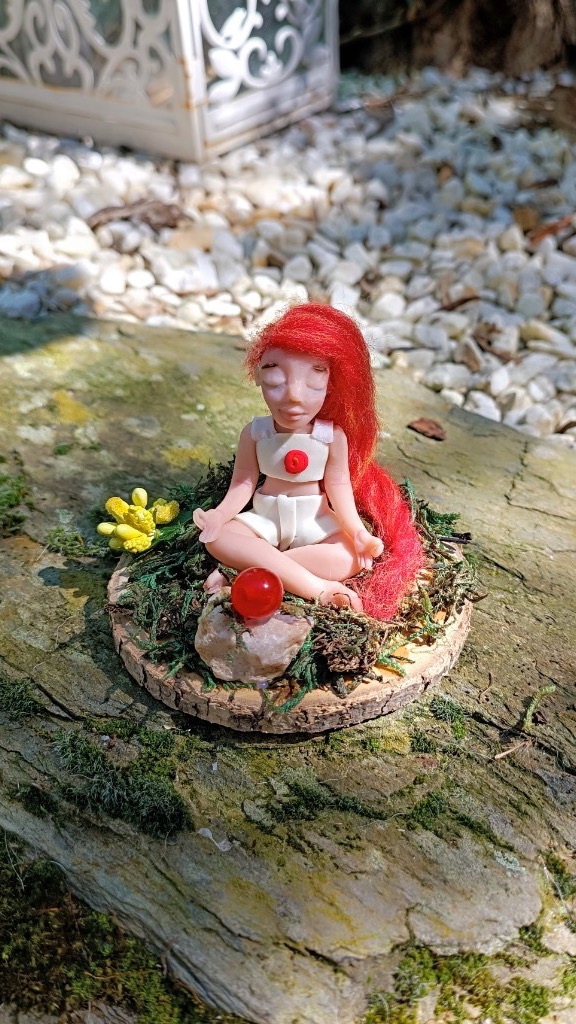 Figura meditando con pelo rojo largo, traje blanco y esfera roja delante